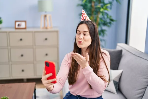 Young woman wearing birthday hat having video call at home