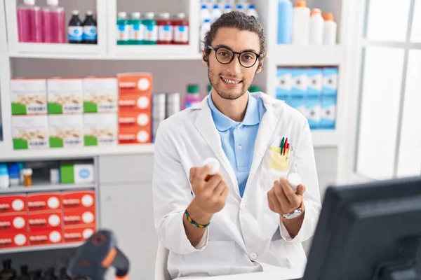Young Hispanic Man Pharmacist Smiling Confident Holding Pills Bottles Pharmacy — Zdjęcie stockowe