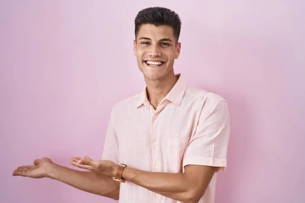 Молодий Іспаномовний Чоловік Стоїть Над Рожевим Тлом Запрошує Увійти Усміхнену — стокове фото