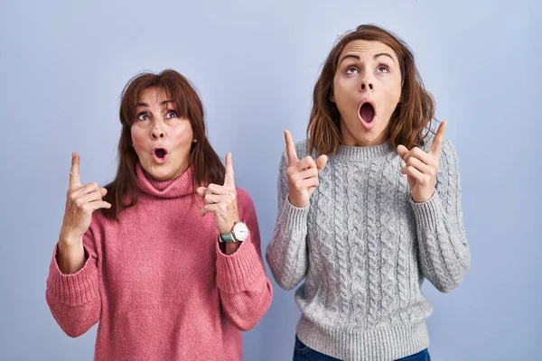 Mother Daughter Standing Blue Background Amazed Surprised Looking Pointing Fingers — Stock Photo, Image