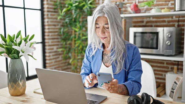 Mulher Cabelos Grisalhos Meia Idade Usando Laptop Smartphone Sentado Mesa — Fotografia de Stock