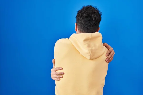 Ισπανόφωνος Που Στέκεται Πάνω Από Μπλε Φόντο Αγκαλιάζοντας Τον Εαυτό — Φωτογραφία Αρχείου