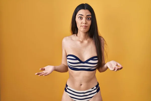 Mujer Morena Joven Con Bikini Sobre Fondo Amarillo Despistado Confundido — Foto de Stock