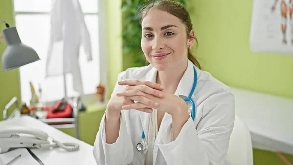 Молода Красива Іспаномовна Жінка Лікар Посміхається Впевнено Сидячи Столі Клініці — стокове фото