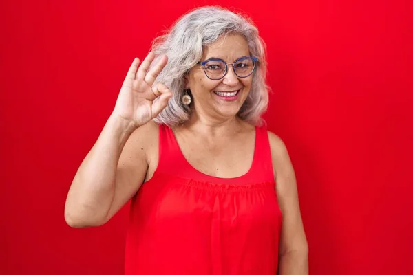 Kırmızı Arka Planda Gri Saçlı Orta Yaşlı Bir Kadın Gülümsüyor — Stok fotoğraf