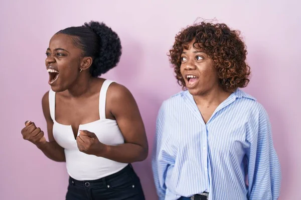 Две Африканские Женщины Стоящие Розовом Фоне Злые Безумные Кричащие Расстроенные — стоковое фото