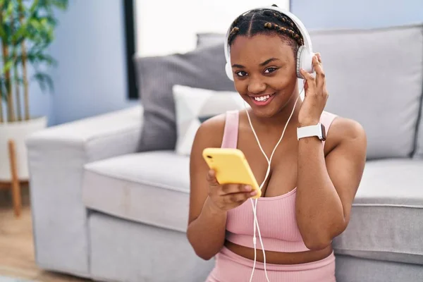 stock image African american woman listening to music sitting on floor at home