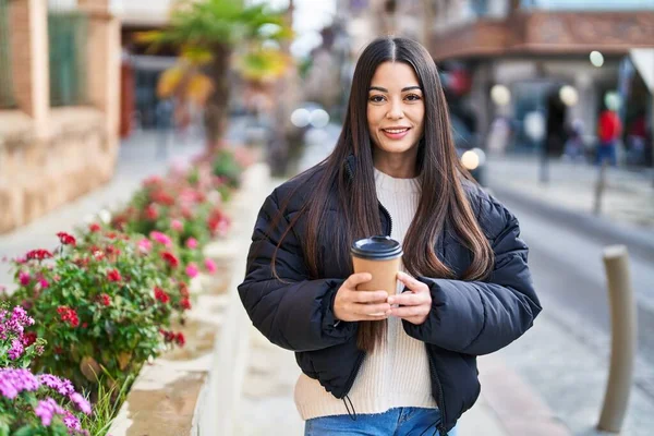 Young beautiful hispanic woman smiling confident drinking coffee at street
