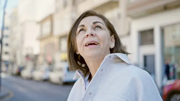 中年惊慌失措的女人带着自信的笑容望着街上的天空 — 图库照片