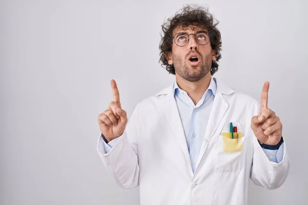 Hispanic Young Man Wearing Doctor Uniform Amazed Surprised Looking Pointing — Stock Photo, Image