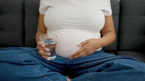 Jonge Zwangere Vrouw Met Glas Water Zittend Bank Thuis — Stockfoto