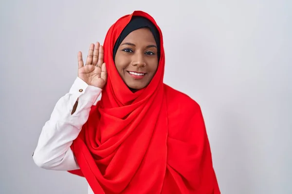 噂やゴシップに耳を傾ける耳の上に手で笑みを浮かべて 伝統的なイスラムヒジャーブスカーフを身に着けている若いアラブの女性 聴覚障害の概念 — ストック写真