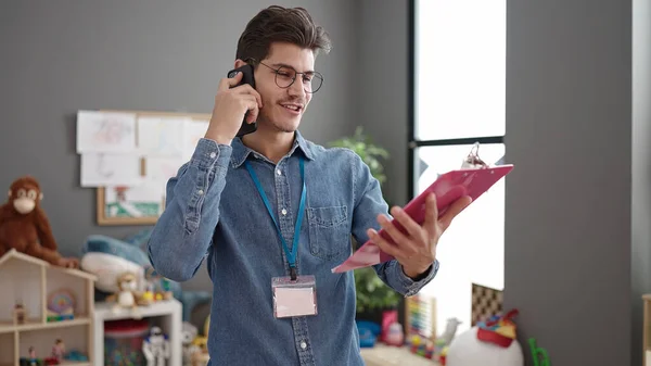 Mladý Hispánský Muž Předškolní Učitel Mluví Smartphone Čtení Dokumentu Školce — Stock fotografie