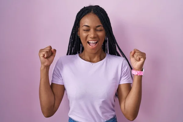 Африканская Американка Косичками Стоящими Розовом Фоне Взволнована Успехом Поднятыми Руками — стоковое фото