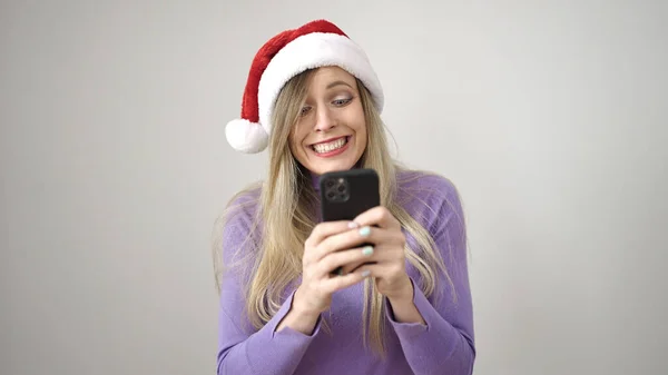 若いですブロンド女性身に着けていますクリスマス帽子使用スマートフォン上の隔離された白い背景 — ストック写真