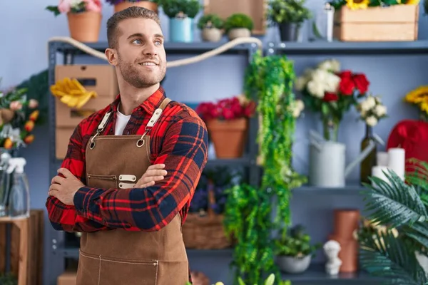 Young caucasian man florist smiling confident standing with arms crossed gesture at flower shop