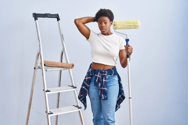 Africano Americano Mulher Segurando Rolo Pintor Louco Assustado Com Mãos — Fotografia de Stock