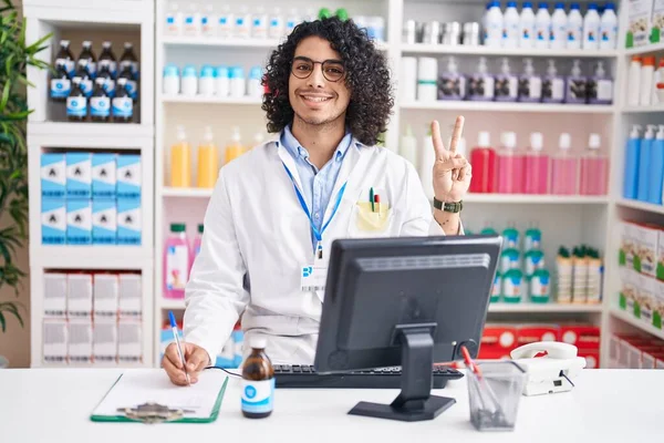 Hispánec Kudrnatými Vlasy Pracující Lékárně Usmívá Dívá Kameru Ukazující Prsty — Stock fotografie