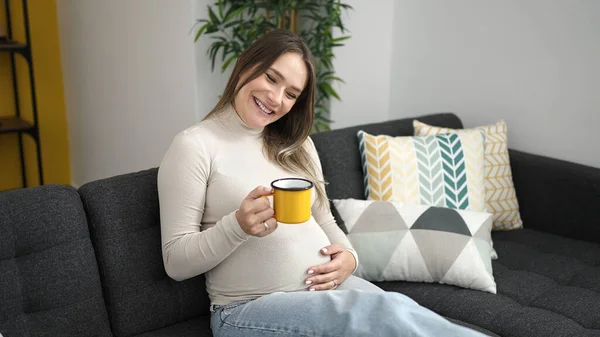 Young Pregnant Woman Drinking Coffee Touching Belly Home — Stock fotografie
