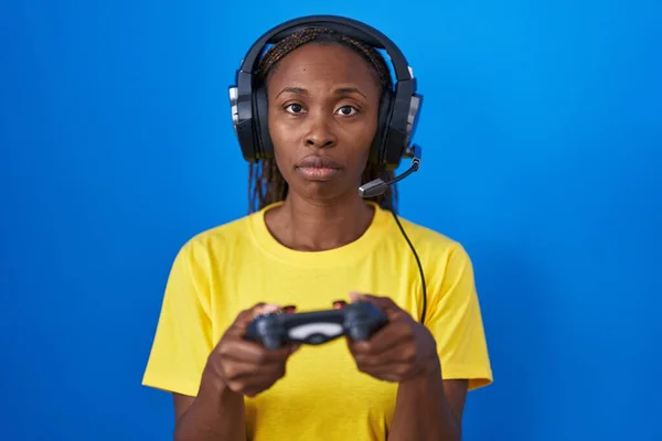玩电子游戏的非洲裔美国女人放松了 脸上有严肃的表情 简单而自然地看着相机 — 图库照片