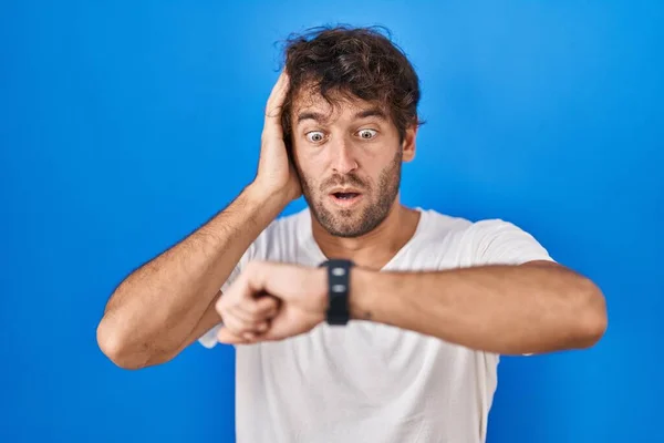 Hispanic Young Man Standing Blue Background Looking Watch Time Worried — ストック写真