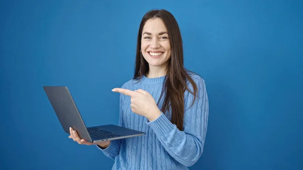 Joven Mujer Caucásica Sonriendo Señalando Computadora Portátil Sobre Fondo Azul —  Fotos de Stock