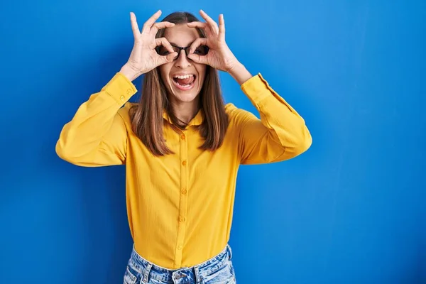 Mavi Arka Planda Duran Gözlüklü Genç Bir Kadın Dürbün Gibi — Stok fotoğraf