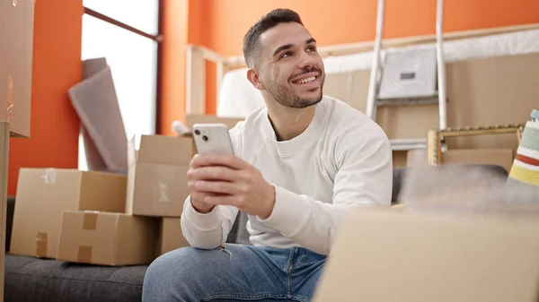 Jovem Hispânico Usando Smartphone Sentado Sofá Uma Nova Casa — Fotografia de Stock