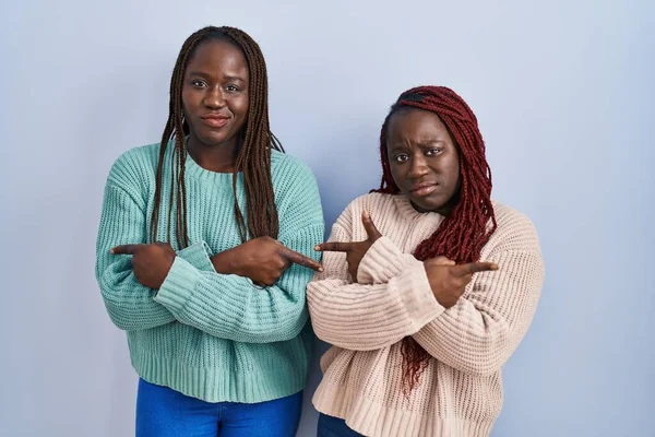 Две Африканки Стоящие Синем Фоне Указывая Пальцами Обе Стороны Разных — стоковое фото