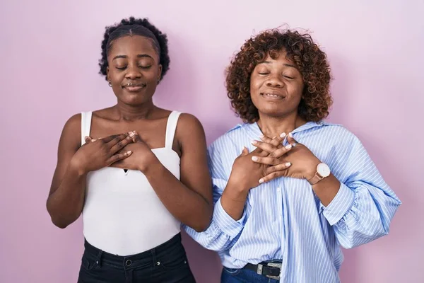 Duas Mulheres Africanas Sobre Fundo Rosa Sorrindo Com Mãos Peito — Fotografia de Stock