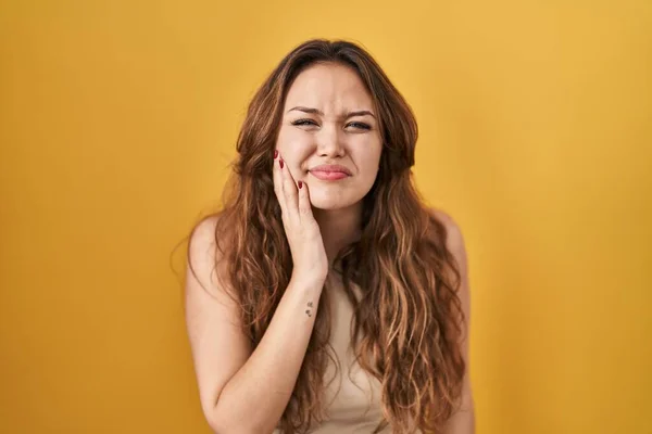 年轻的惊慌失措的女人站在黄色的背景上用手摸着嘴 因为牙齿疼痛或牙病 脸上带着痛苦的表情 — 图库照片