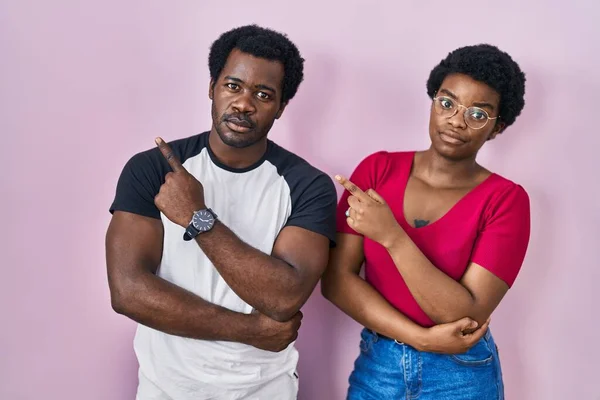 Mladý Africký Americký Pár Stojící Nad Růžovým Pozadím Ukazuje Ukazováčkem — Stock fotografie