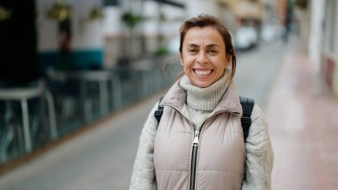 Orta yaşlı İspanyol kadın sokakta kendine güvenerek gülümsüyor.