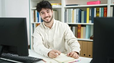 Genç İspanyol öğrenci kütüphane üniversitesinde bilgisayar notu kullanıyor.