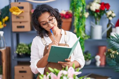 Çiçekçide defter okuyan güzel bir İspanyol kadın.