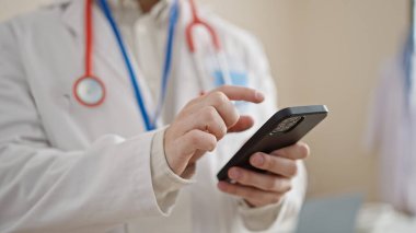 Genç İspanyol doktor klinikte akıllı telefon kullanıyor.