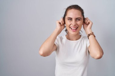 Güzel esmer kadın izole edilmiş arka planda duruyor. Gülümsüyor, kulakları parmaklarıyla çekiyor. Komik bir jest. deneme sorunu 