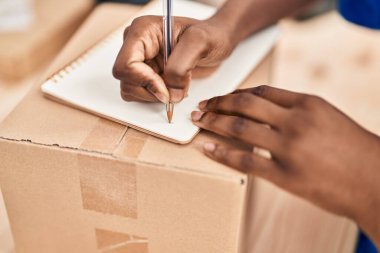 African american woman ecommerce business worker writing on notebook at office