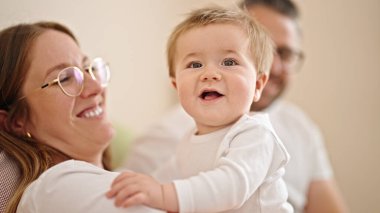 Anne, baba ve bebeğin ailesi birlikte yatak odasında oturuyor.