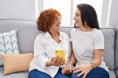 Evde akıllı telefon kullanan iki kadın anne ve kız.