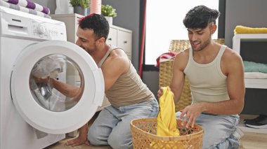 Çamaşır odasında kendine güveni olan iki erkek çamaşır yıkıyor.