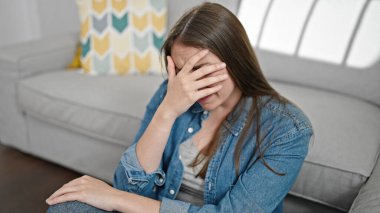 Genç ve güzel İspanyol kadın evde yerde otururken strese girdi.