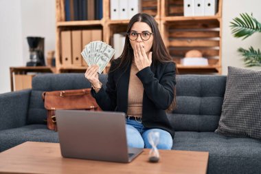 Muayenehanede çalışan genç bir kadın elinde parayla ağzı kapalı, şok olmuş ve hata yapmaktan korkan bir kadın. şaşırmış ifade 