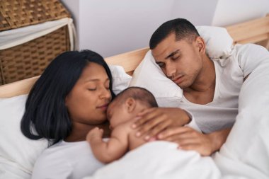 Hispanic family lying on bed sleeping at bedroom