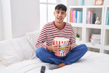Genç İspanyol adam yatakta oturmuş patlamış mısır yiyor. Bir film seyrediyor. Seksi bir ifadeyle kameraya bakıyor.. 