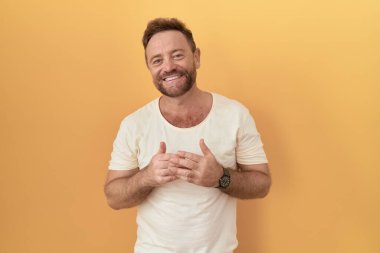 Sarı arka planda sakallı orta yaşlı bir adam el ele tutuşup gülümseyerek gevşemiş ve neşeliydi. Başarı ve iyimserlik 