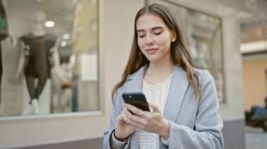 Sokakta akıllı telefon kullanan genç İspanyol kadın.