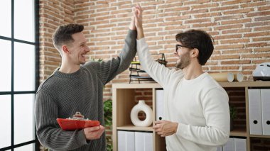 İki erkek iş ortağı beşlik çakıyor, eller havada.