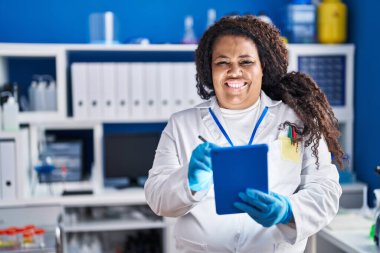 Afrika kökenli Amerikalı bilim kadını. Laboratuvarda dokunmatik kağıda kendinden emin bir şekilde yazıyor.