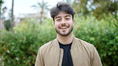 Parkta kendinden emin gülümseyen İspanyol genç adam.